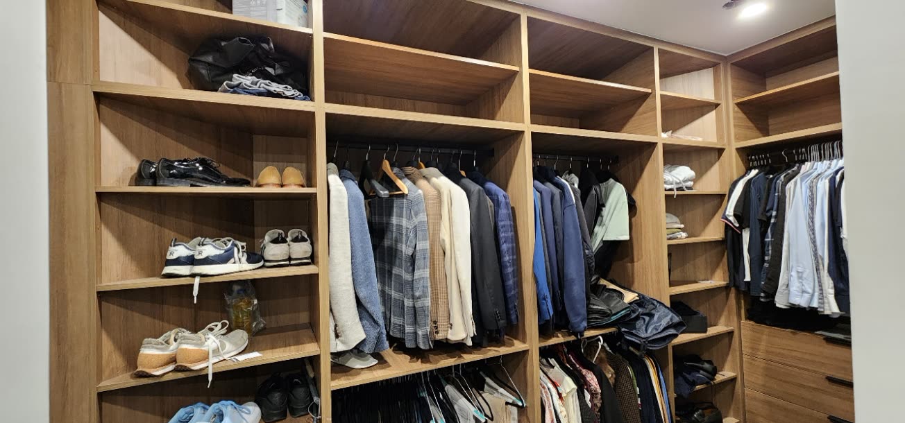 Organized walk-in closet in warm wood with open shelving and drawers by iKitchen Cabinetry