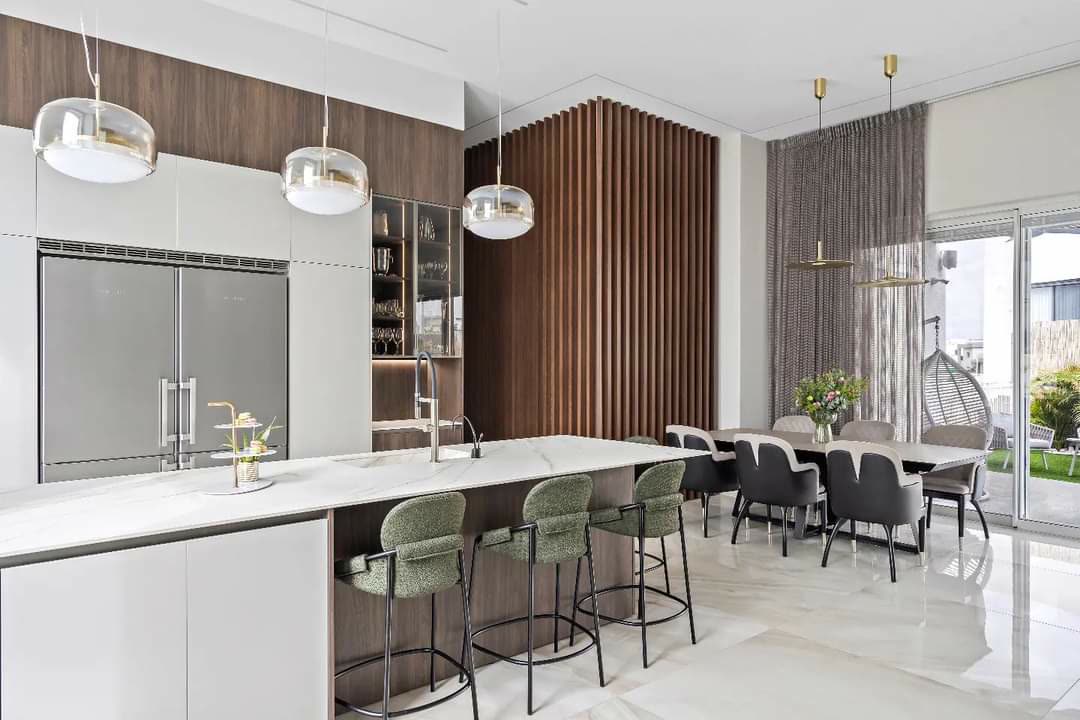 White contemporary kitchen with walnut slat accents and green velvet stools by iKitchen Cabinetry