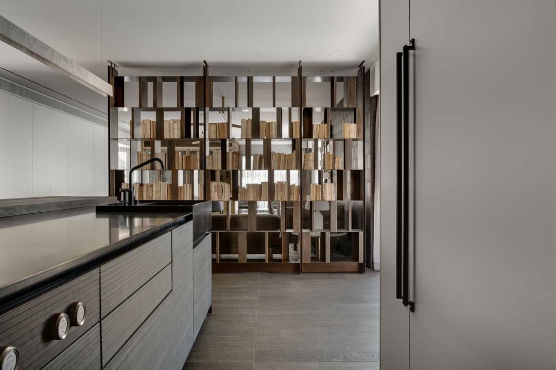 Stone-clad European kitchen island with bronze room divider by iKitchen Cabinetry