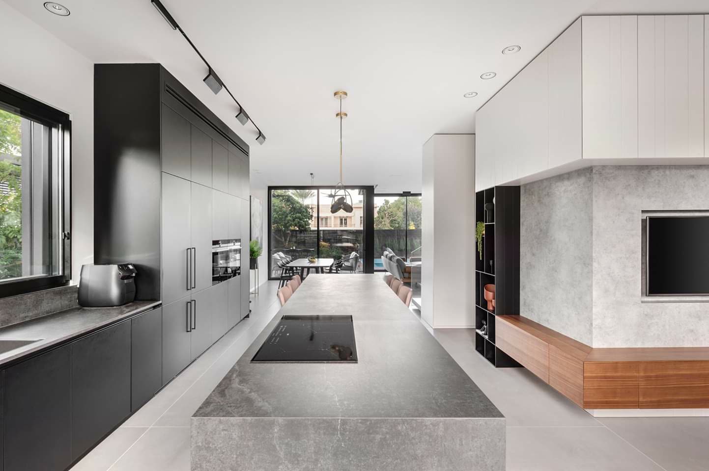 All-black modern kitchen with gold-toned counter stools by iKitchen Cabinetry