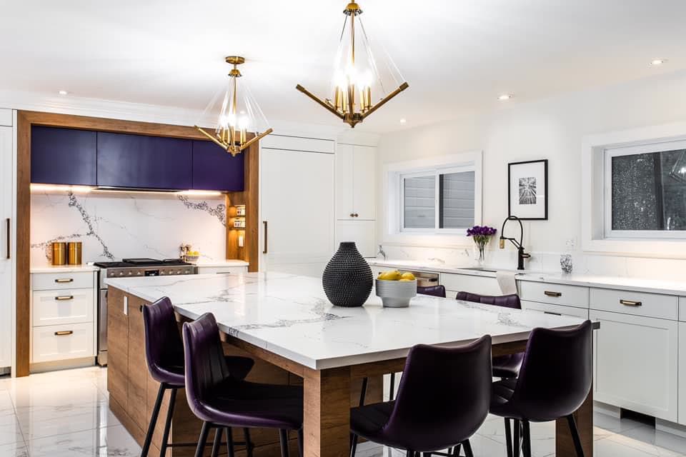 Classic white shaker kitchen with navy island and marble counters by iKitchen Cabinetry