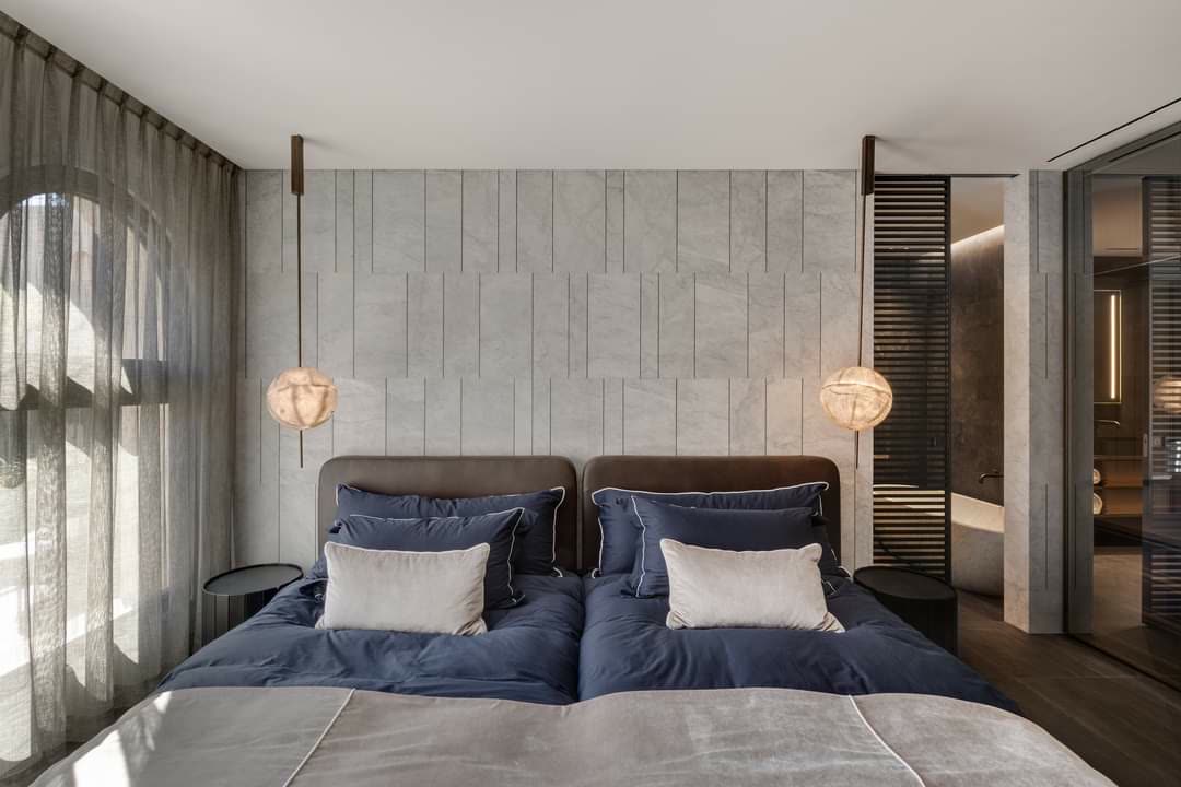 Travertine-paneled master bedroom feature wall by iKitchen Cabinetry